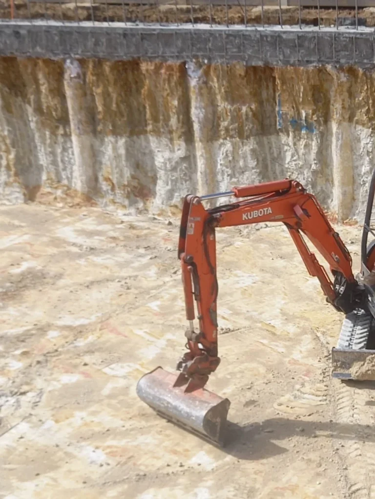 Orange excavator digging a large basement with bored piers
