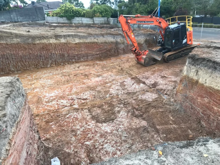 Excavator digging a new basement on a residential block.