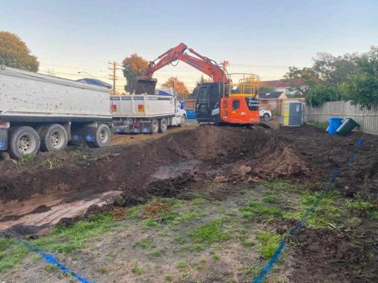 Excavator loading a truck with dirt from a residential site cut.