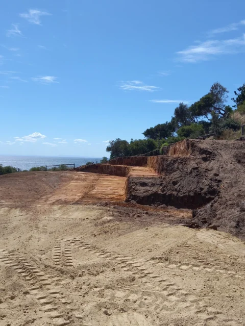 Tiered site cut on an open construction site with cleared land and ocean view.