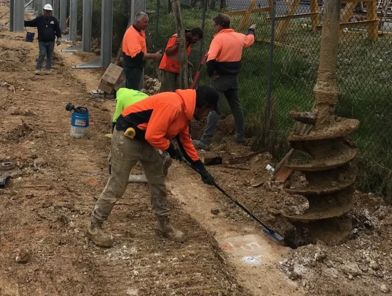 Men working on an excavation project with a large post hole auger